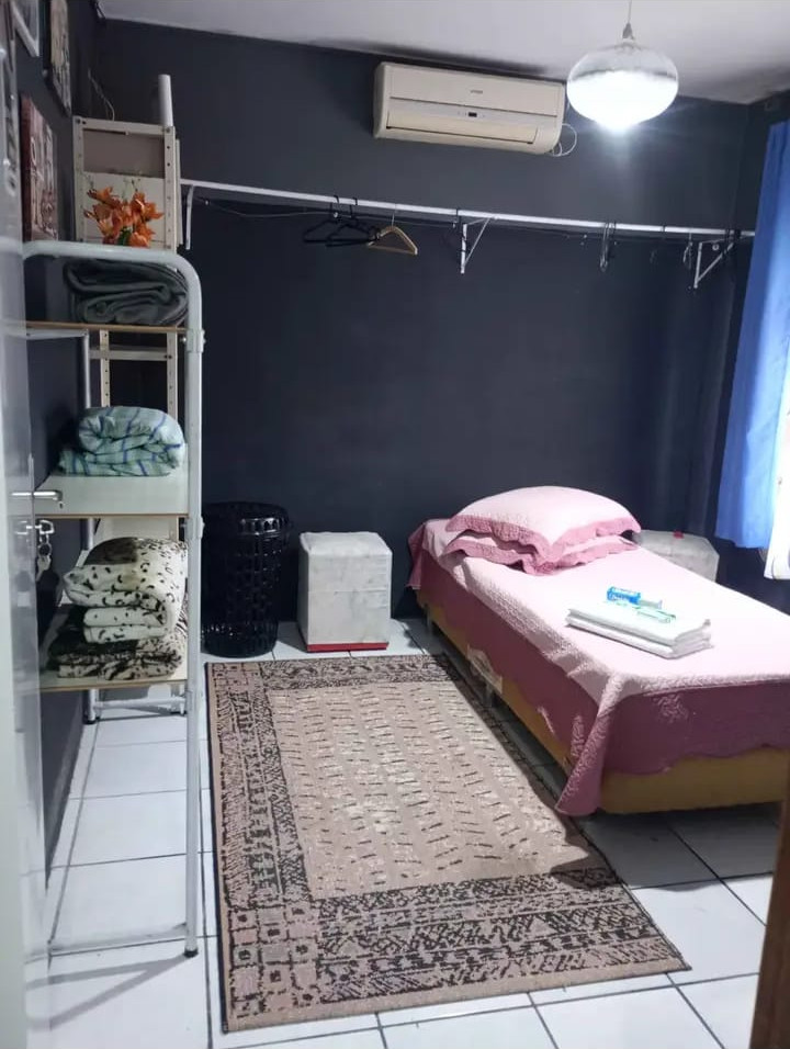 Quarto 2 da Pousada Gaspar: cama de solteiro, ar-condicionado e arara com cabides